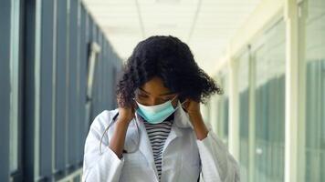 African american female doctor puts on medical mask in modern clinic. Stop virus video