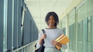africano americano mujer estudiante con un libros en el universidad. nuevo moderno completamente funcional educación instalación. concepto de en línea educación video