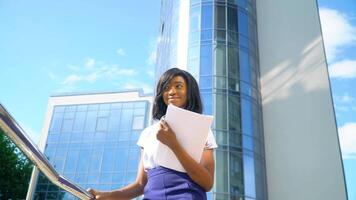 Adult african american young businesswoman works with documents near modern office building video