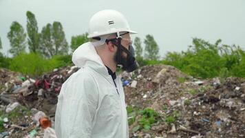 Activist scientist with protective mask on landfill. Environmental pollution concept video