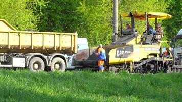 Ternopil, Ukraine, May 2020. Team of workers in protective uniforms work on road construction. Workers transportation equipment construction industrial machine building video