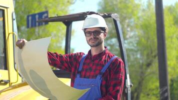 retrato de el trabajador en uniformes y blanco casco en contra el antecedentes de un la carretera construcción sitio video