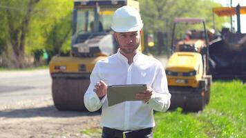 Worker with personal tablet on road works. Manager of the repair works on road, inputs data in his computer video