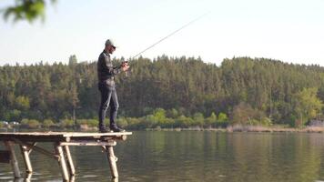 Fisherman cast fishing rod in lake or river water. Fishing on lake video