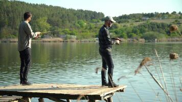 dois homens estão pescaria em a lago. fiação pescaria predatório peixe video