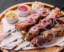 kebabs from pork on skewers on wooden board photo