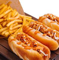 Hot dogs and fried potatoes on wooden board photo