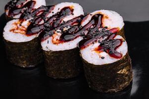 sushi roll maki with eel and unagi sauce on a black plate photo