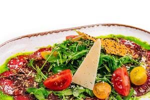 Beef carpaccio with Parmesan and arugula on plate isolated photo