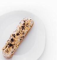 Eclair with cream and chocolate on plate photo