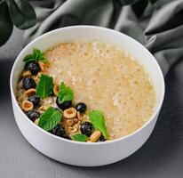 Oatmeal porridge with hazelnuts and blueberries in bowl photo