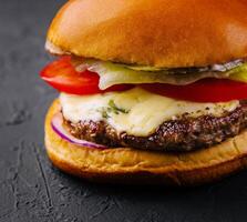 delicioso hamburguesa con queso en un negro antecedentes foto