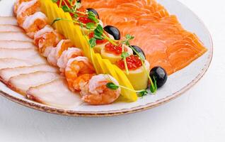 salmon, white fish, shrimp and red caviar on plate photo