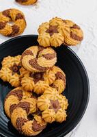 crumbly cookies with chocolate on black plate photo