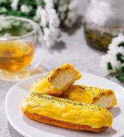 Fresh tasty eclair on white plate and cup of tea photo