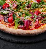 Italian pizza with prosciutto, arugula and cherry tomatoes photo