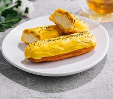 Fresh tasty eclair on white plate and cup of tea photo