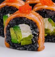 Black rice sushi rolls with salmon close up photo