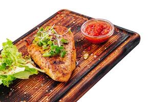 chicken breast with spicy sauce on wooden board photo