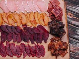 various jerky or dried meats and sausage on a board photo