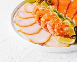 salmon, white fish, shrimps and olives on plate photo