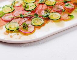 Buffet serving of pickled salmon slices with radish, cucumber photo