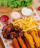 fried nuggets and spicy chicken legs, wings and french fries potatoes photo