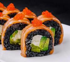 negro arroz Sushi rollos con salmón en blanco plato foto