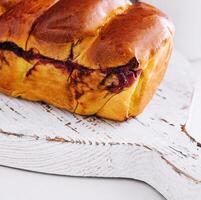 Delicious baked bun with cherry on white wood photo