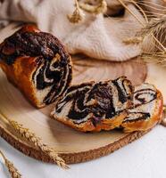 Wooden board with tasty cut poppy seed bun photo