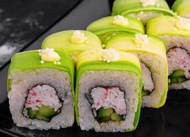 aguacate Sushi rodar con cangrejo en negro plato foto