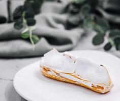 eclair with meringue on plate close up photo