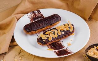 chocolate eclairs with almonds on plate photo
