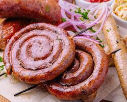 Grilled sausages on a wooden board with sauce photo