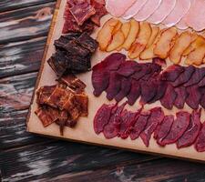 various jerky or dried meats and sausage on a board photo