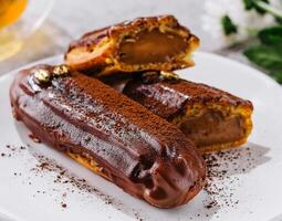 Tasty chocolate eclairs on plate close up photo