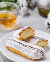 Fresh tasty eclair on white plate and cup of tea photo