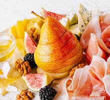 Italian antipasto with prosciutto, cheeses, nuts and fruits photo