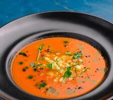 Tomato gazpacho soup on black plate photo