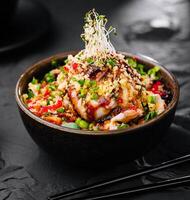 Salad with eel and couscous on black bowl photo