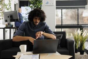 Young arab executive manager searching solution for marketing strategy while working on laptop. Company start up project employee analyzing sales report data in business office photo