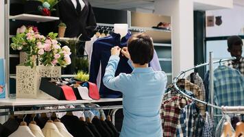 empleado trabajando a boutique apertura, poniendo formal vestir en maniquí. compras centrar gerente arreglando de moda mercancías y accesorios, nuevo Moda colección en ropa Tienda foto