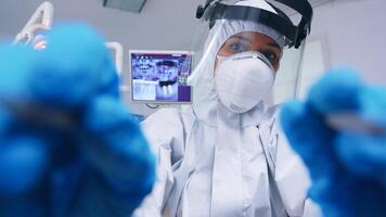 pov de dentista en ppe traje en contra codicioso trabajando en paciente boca hygine en dental oficina con nuevo normal. estomatólogo vistiendo la seguridad engranaje en contra coronavirus durante cuidado del calor cheque de paciente. foto