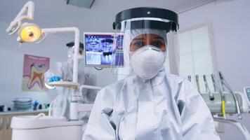 dentista pov en codicioso traje examinando boca hygine utilizando dental herramientas en estomatológico oficina con nuevo normal. estomatólogo vistiendo la seguridad engranaje en contra coronavirus durante cuidado del calor cheque de paciente. foto