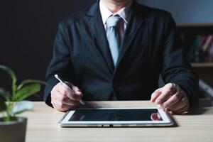 businessman using tablet computer and taking notes in planning. which is payment online, sits on the chair in the living room at home on a laptop. The concept of finance and online shopping. photo