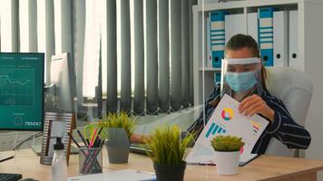 Businesswoman with visor and protection mask working in new normal business office. Freelancer discussing with colleague in financial company respecting social distance during global pandemic. photo