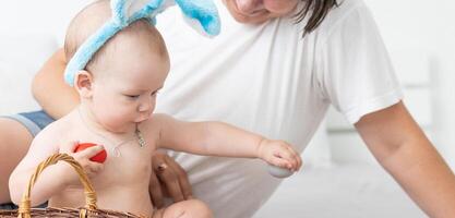 happy family celebrating easter mother and baby bunny ears at home with colorful eggs photo