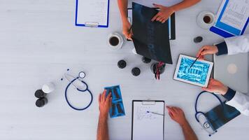 Top view of fast forward shot of doctors having medical conference sitting on desk using digital technology, taking notes, researching and checking appointments. Copy space flat lay time lapse concept photo