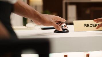 Business trip guests ready to book in their reservation at hotel lobby reception counter. African american guests ringing concierge bell at front desk during check in process photo