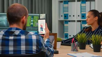 Disabled freelance videographer talking on video call with doctor in work time while creates content sitting in wheelchair in modern company office. Creator blogger working from photo studio.